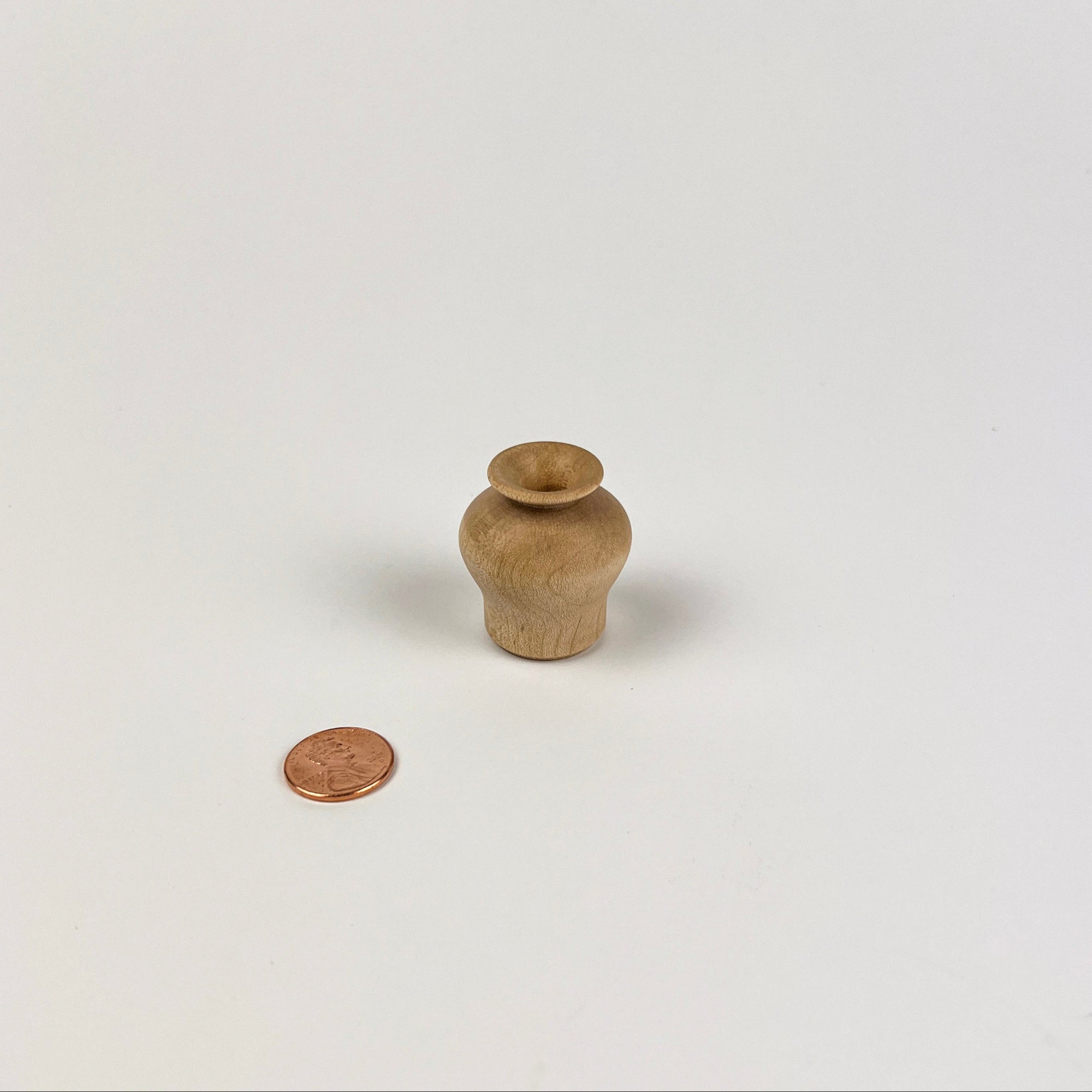 Small wooden vase on a white background with a coin for scale