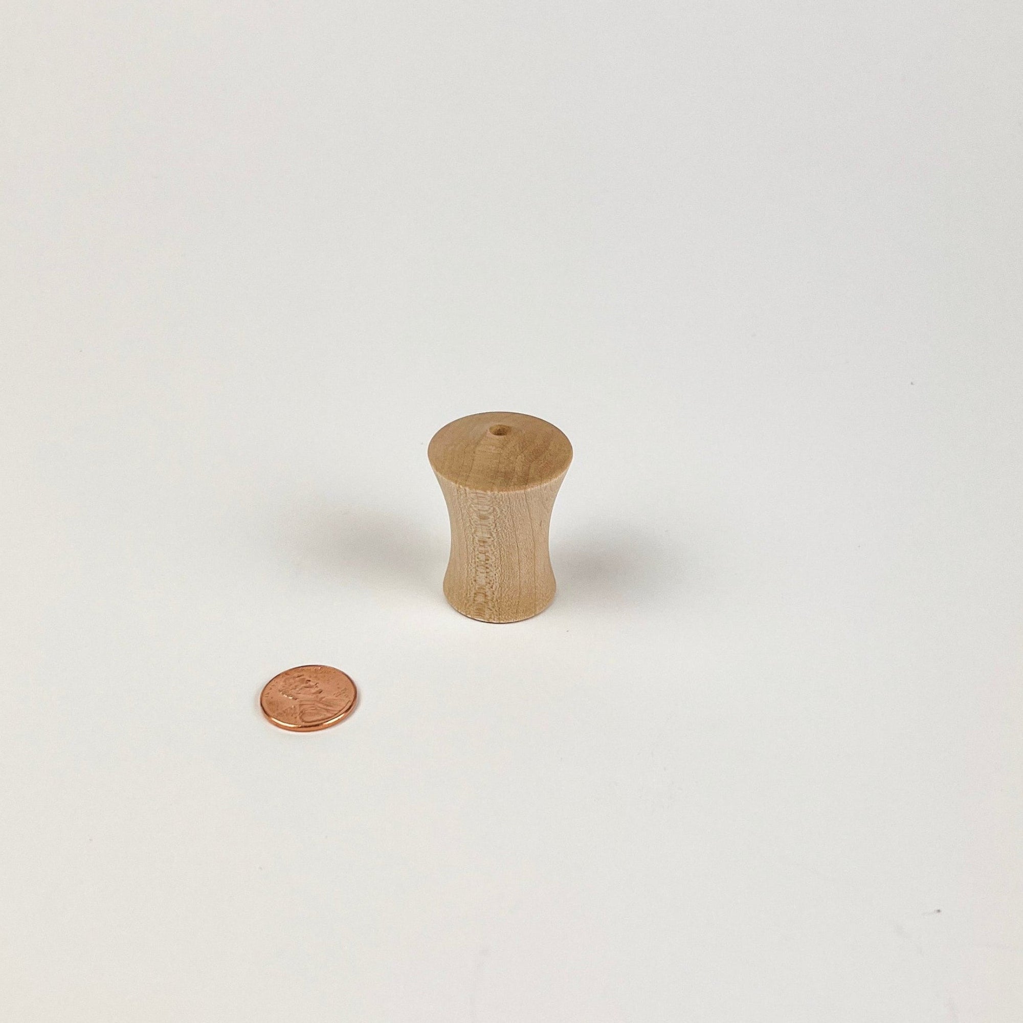 Small wooden vase next to a penny on a white background