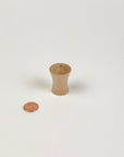 Small wooden vase next to a penny on a white background