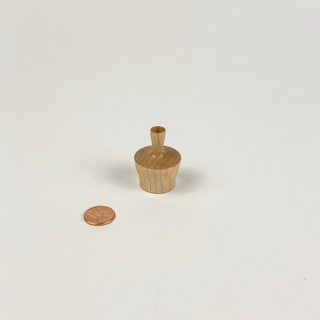 Small wooden vase next to a penny on a white background