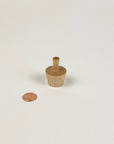 Small wooden vase next to a penny on a white background