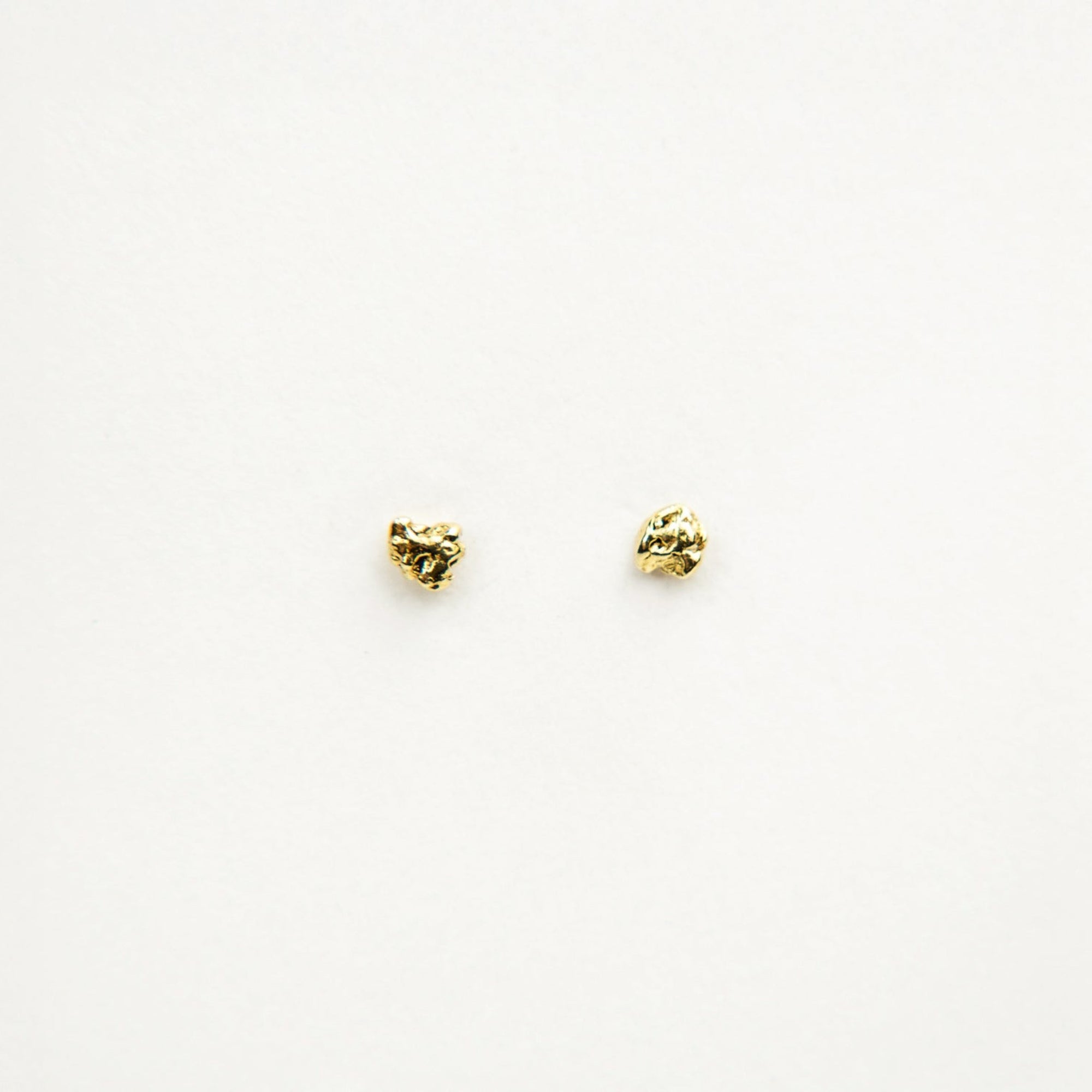 Two gold nugget earrings on a white background
