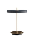 Modern table lamp with black shade and gold base on a white background