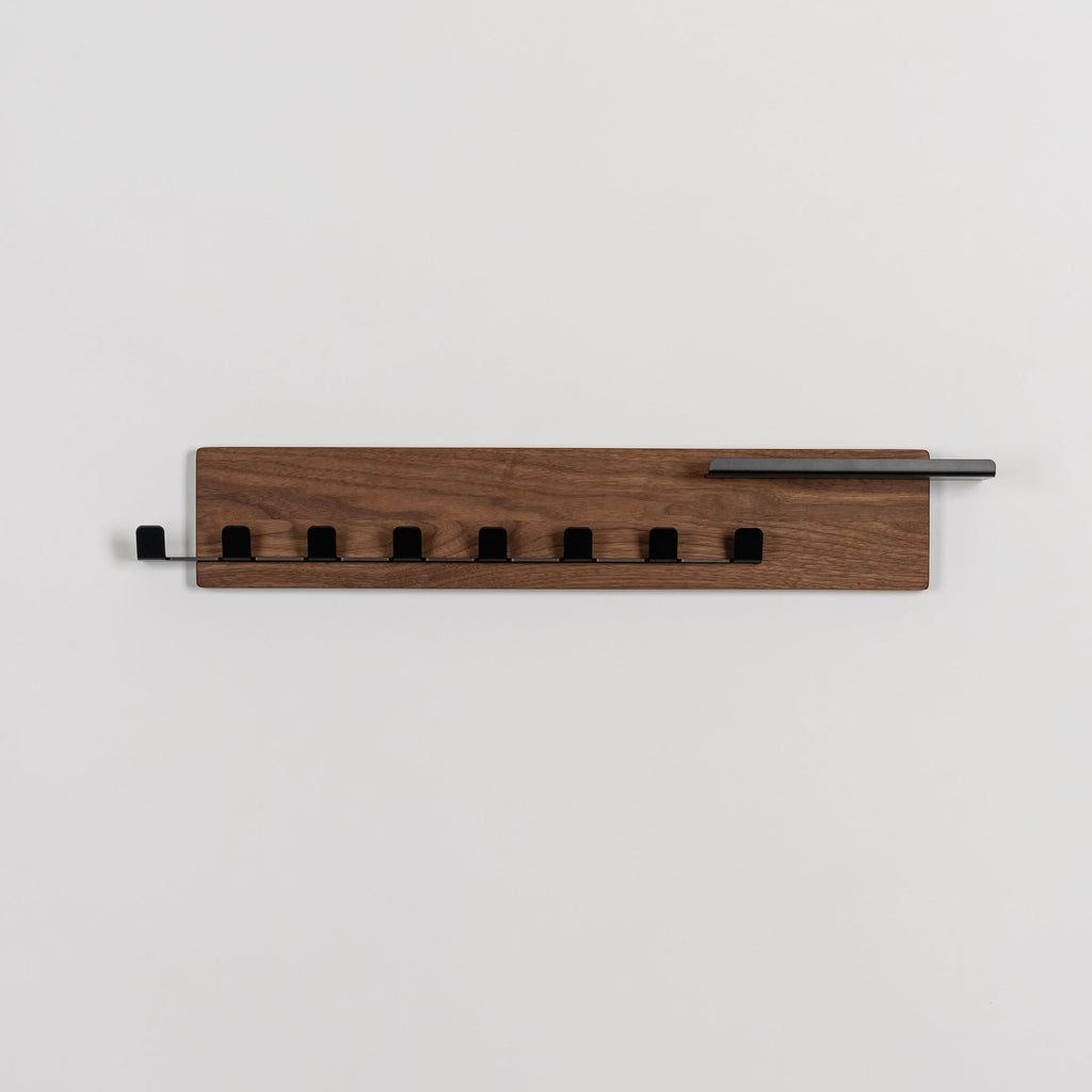 Wooden wall-mounted coat rack with five hooks on a light gray background