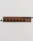 Wooden wall-mounted coat rack with five hooks on a light gray background