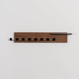 Wooden wall-mounted coat rack with five hooks on a light gray background