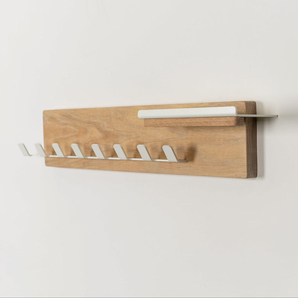 Wooden wall-mounted rack with white hooks on a light gray background