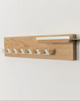 Wooden wall-mounted rack with white hooks on a light gray background