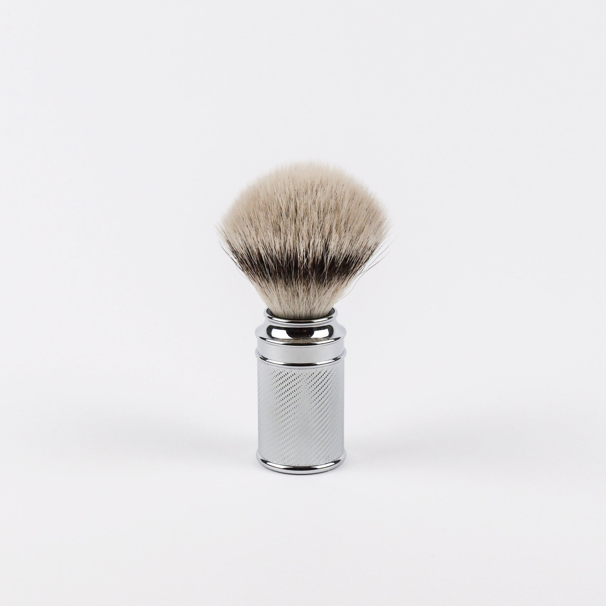 Shaving brush with textured chrome finish on a white background