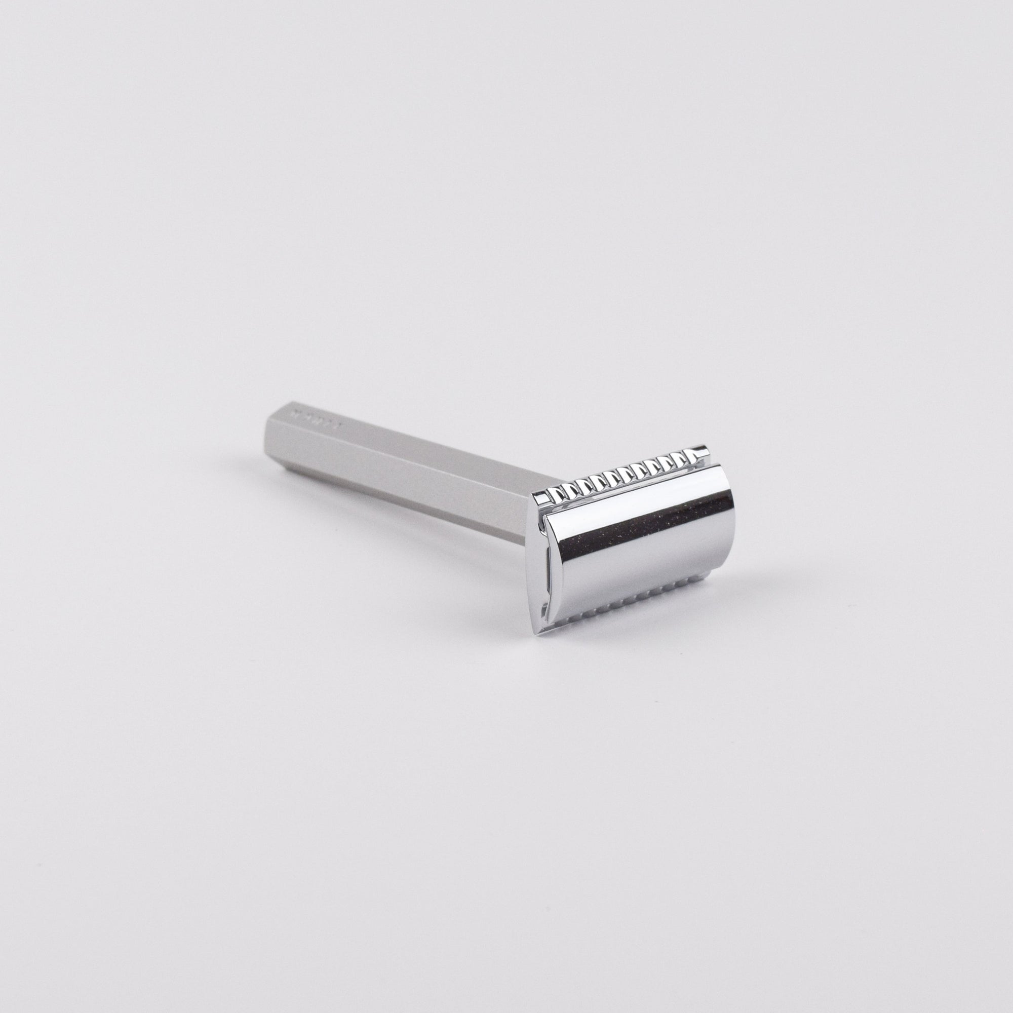 Silver safety razor on a light gray background