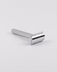 Silver safety razor on a light gray background