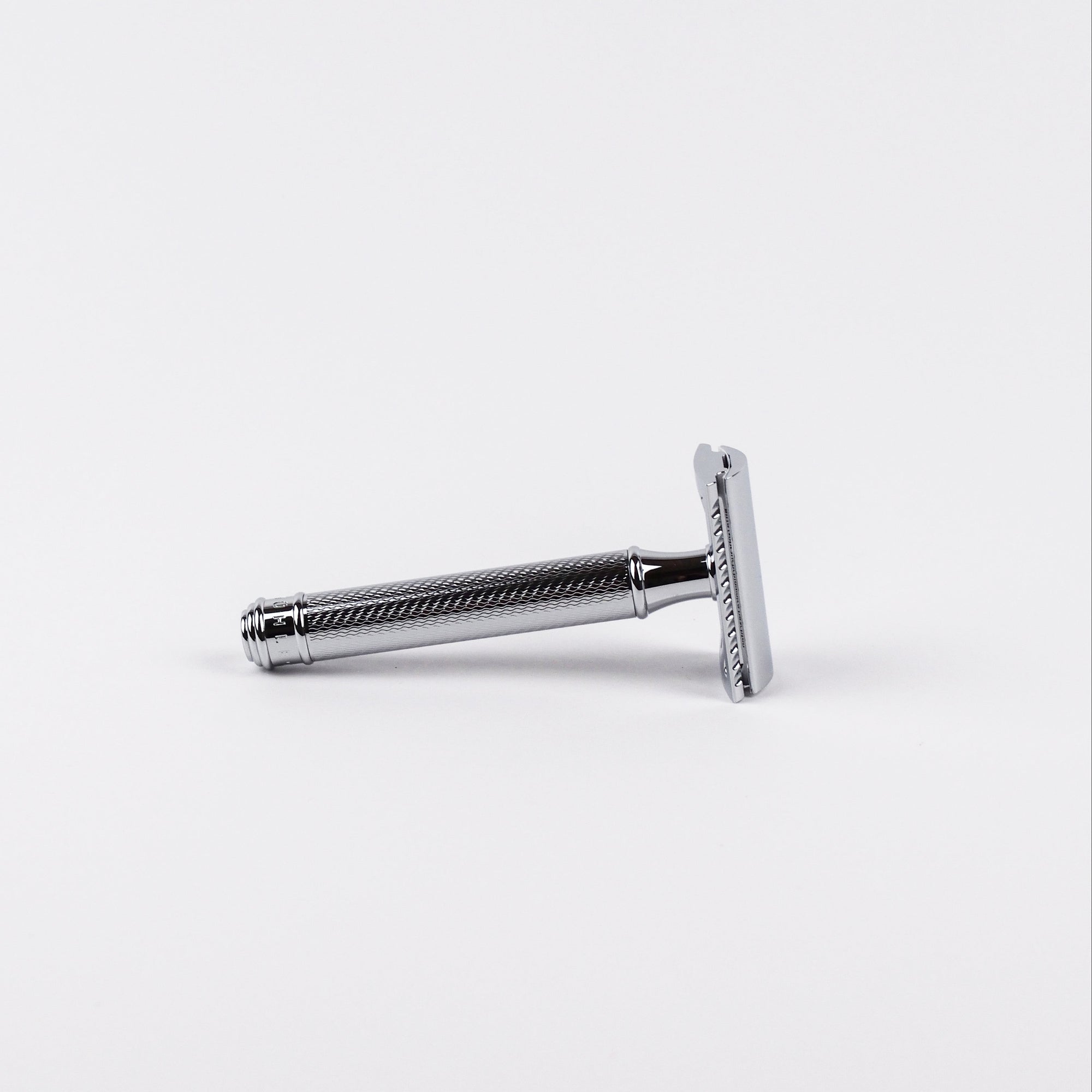 Chrome safety razor with a textured handle on a white background