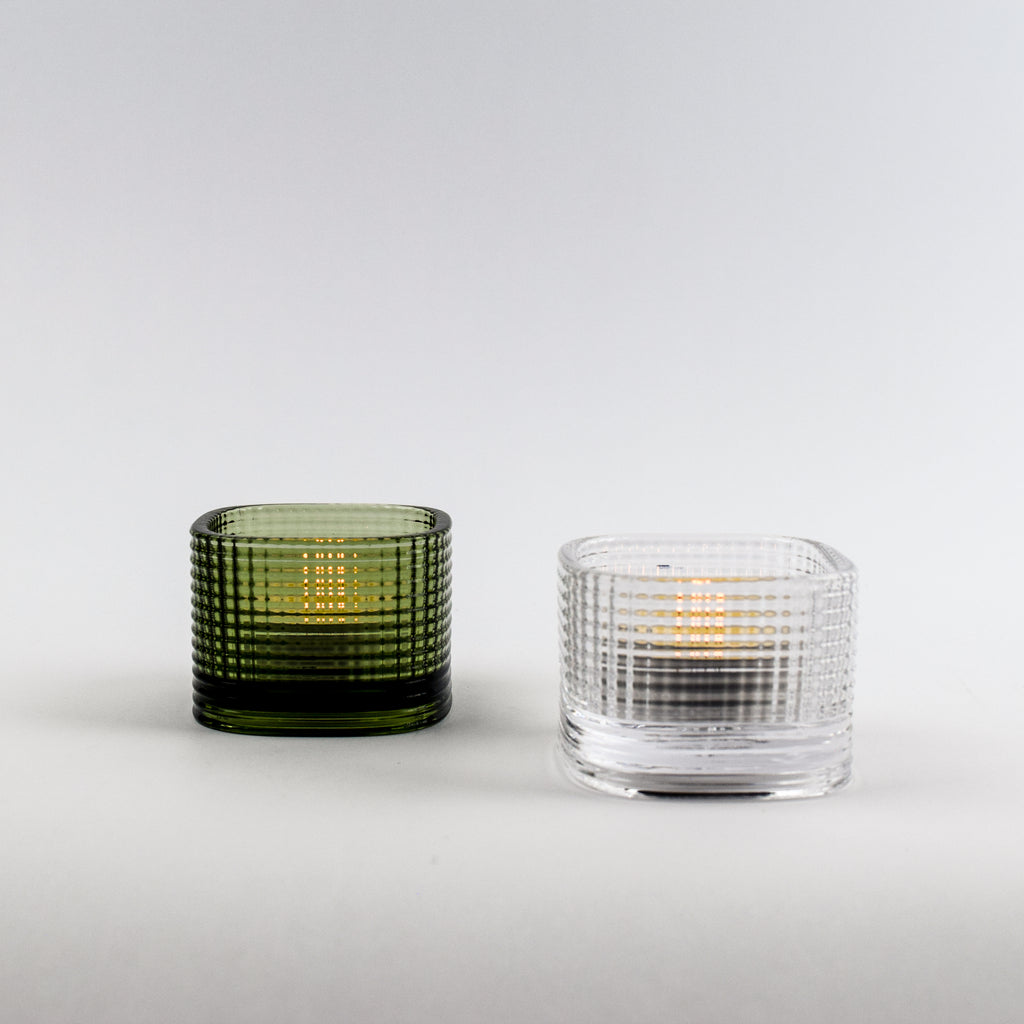Two glass candle holders, one green and one clear, on a white background