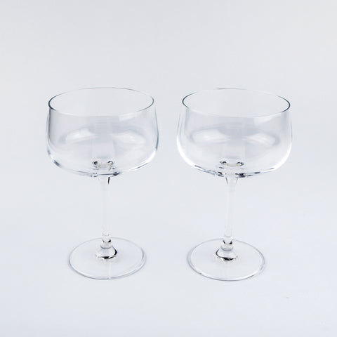Two clear glass coupe glasses on a light gray background