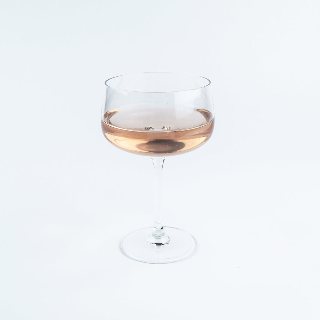 Wine glass with a small amount of rose wine on a white background