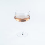 Wine glass with a small amount of rose wine on a white background