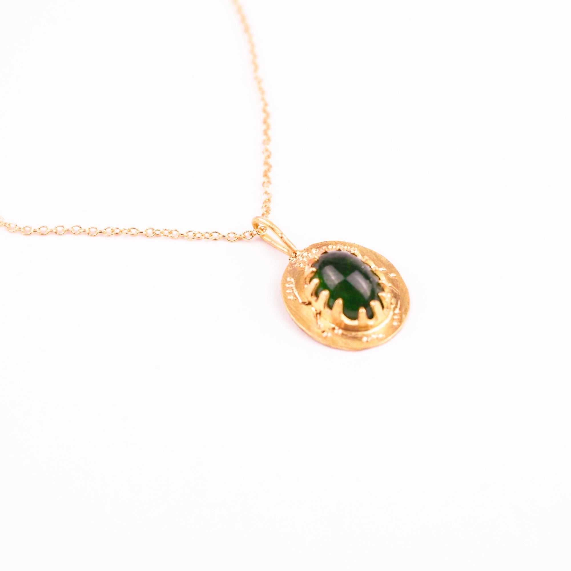 Gold necklace with a green pendant on a white background