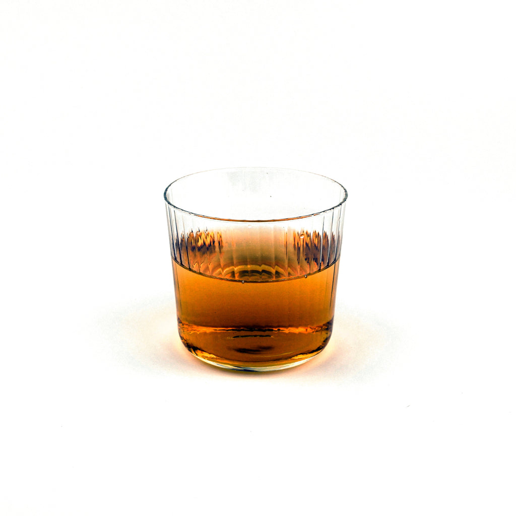Glass of amber liquid on a white background