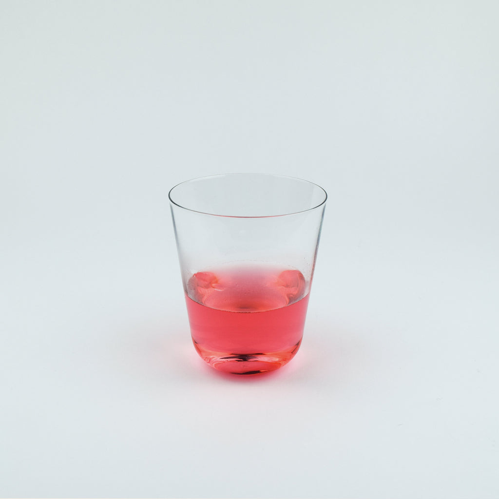 Clear glass with red liquid on a white background