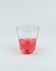 Clear glass with red liquid on a white background