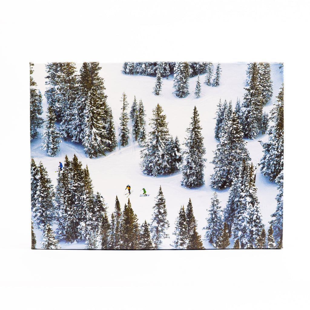 Jigsaw puzzle with skiers descending a snowy slope with trees on a white background