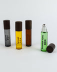 Four roller bottles with different colored liquids and black caps on a white background