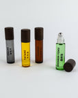 Four roller bottles with different colored liquids and labels on a white background