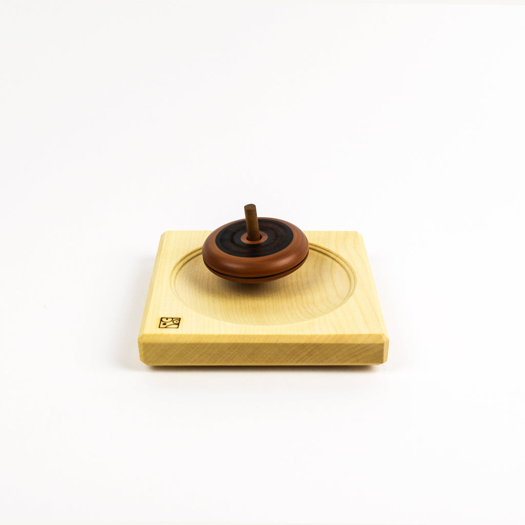 Wooden top on a wooden plate on a white background
