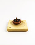 Wooden top on a wooden plate on a white background