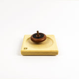 Wooden top on a wooden plate on a white background