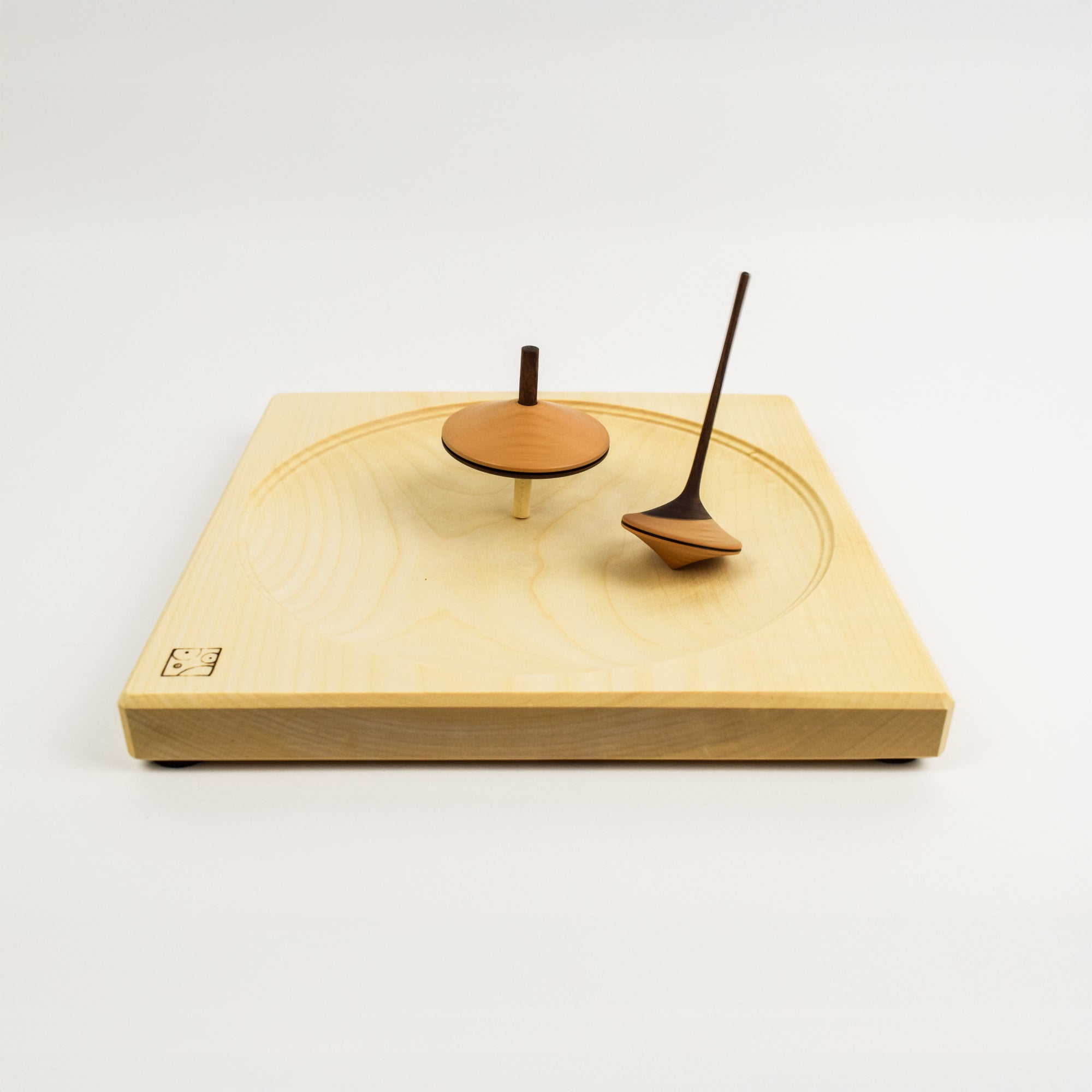 Wooden spinning plate with two tops against a white background