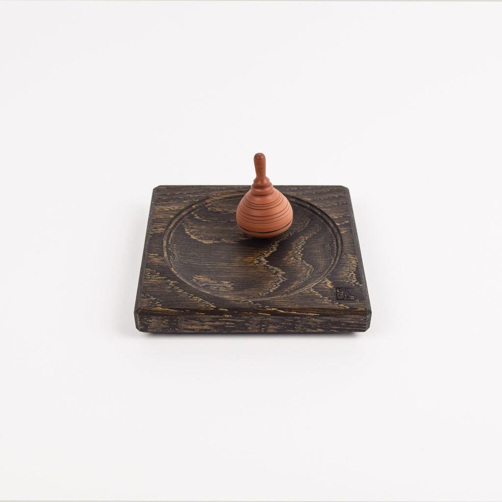 Small spinning top on a wooden base against a white background