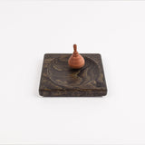 Small spinning top on a wooden base against a white background