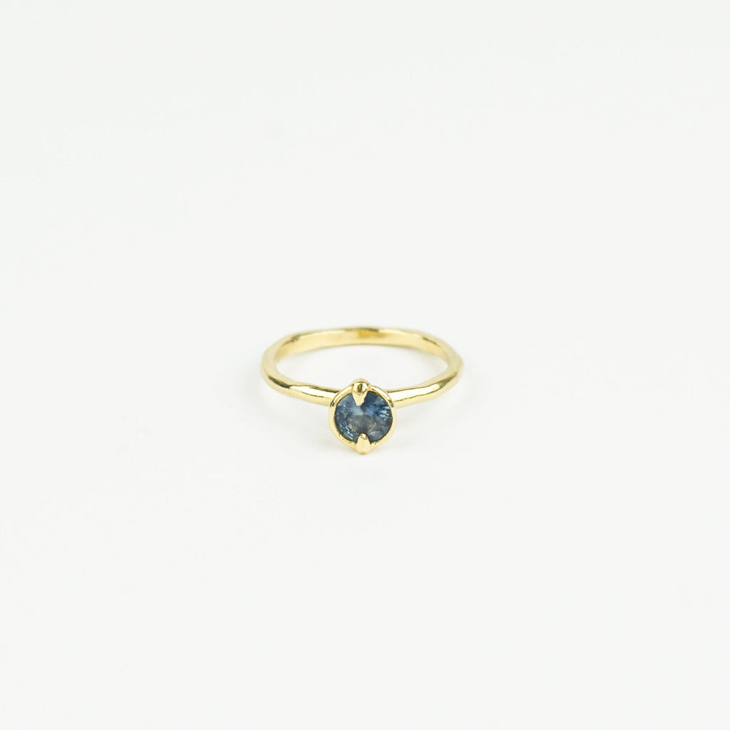Gold ring with a blue gemstone on a white background