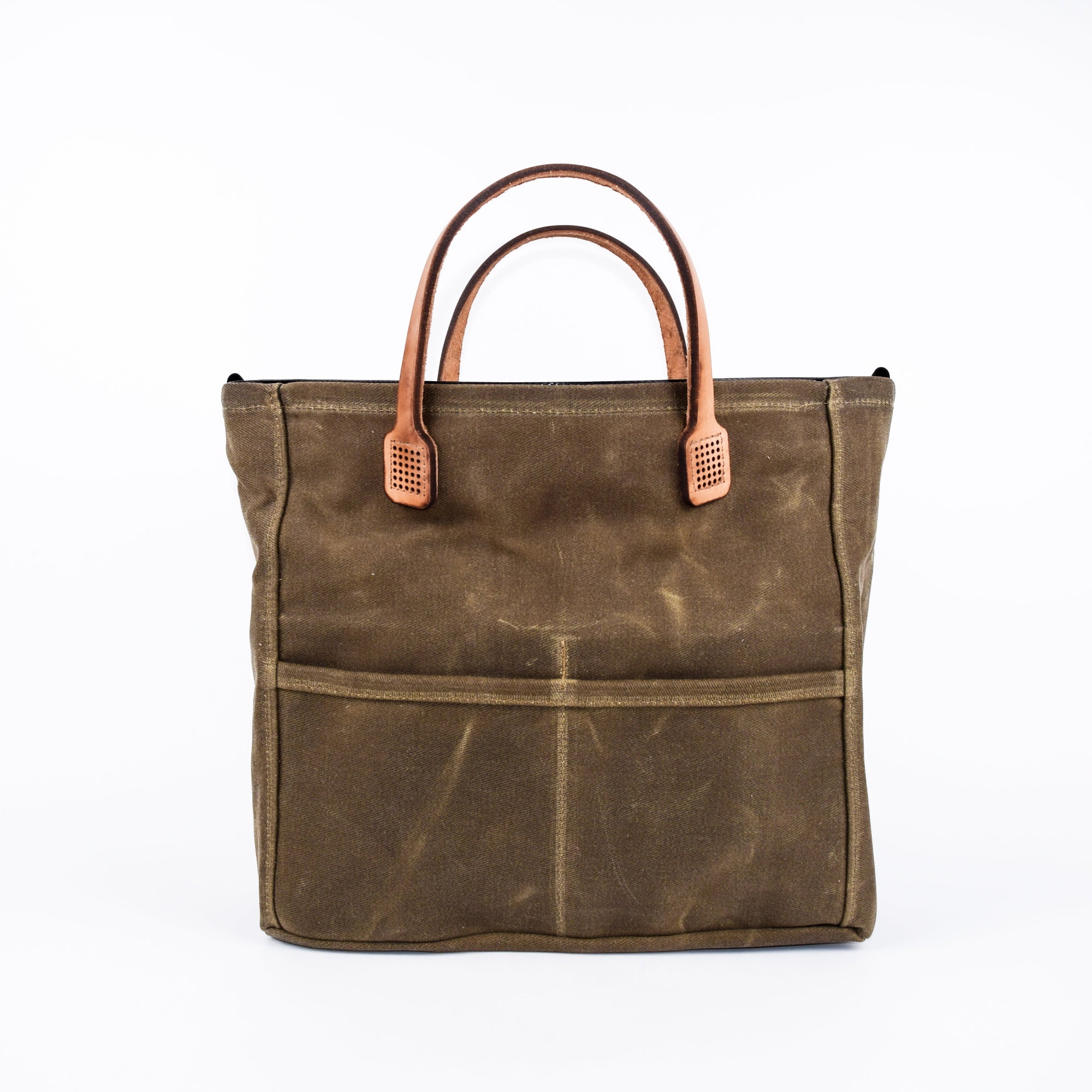 Brown waxed canvas tote bag with tan leather handles on a white background