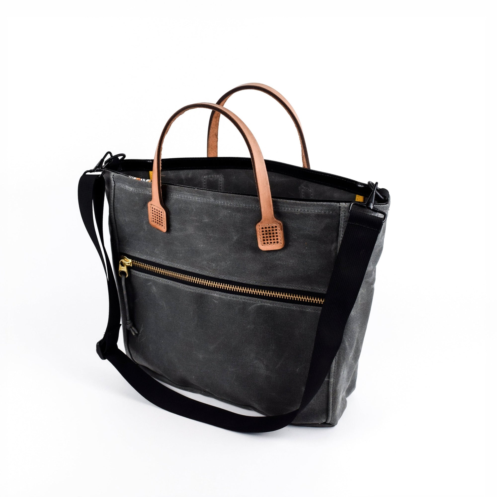Gray waxed canvas  tote bag with tan leather handles and accents on a white background