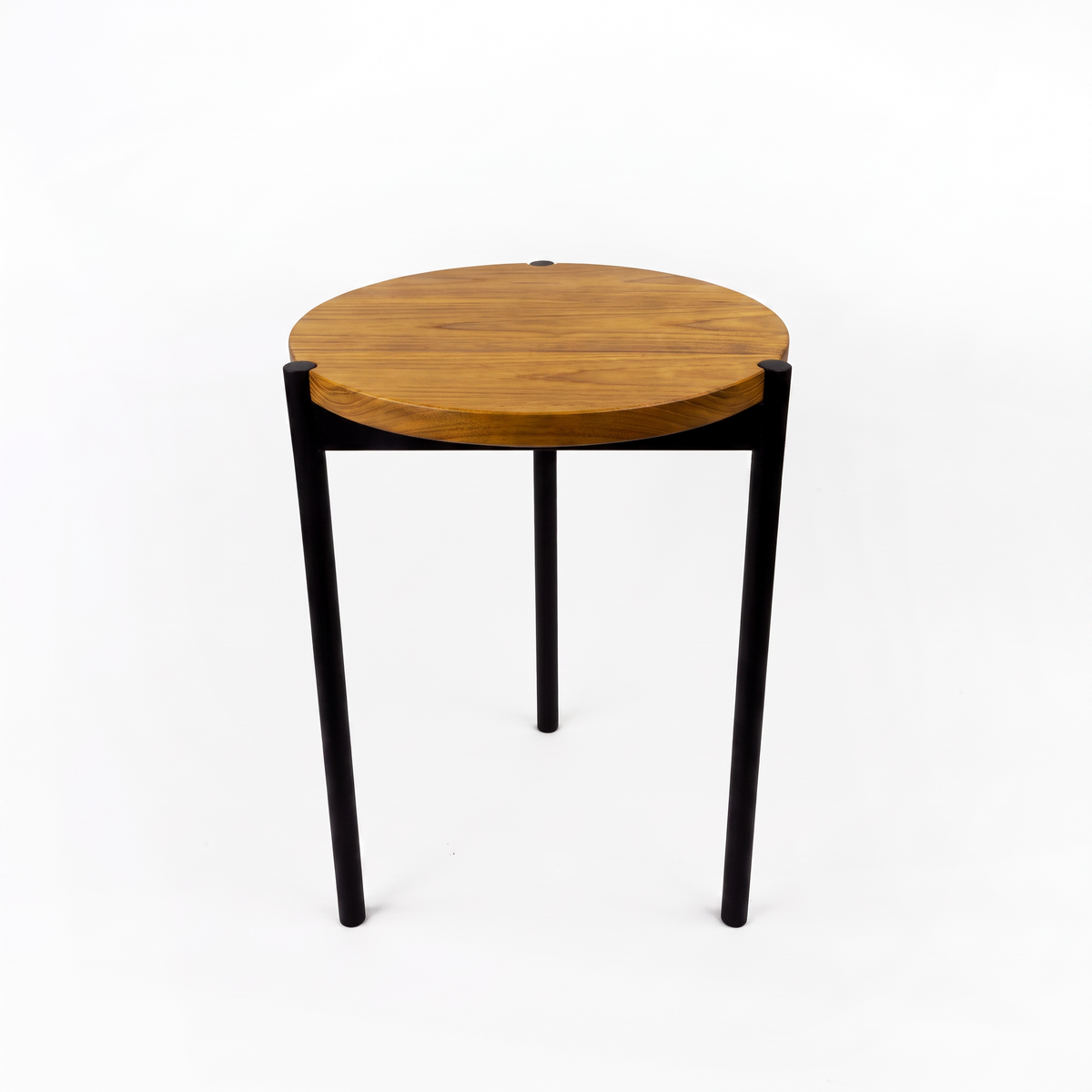 A modern round side table with a warm medium-brown wood top and slim black metal legs, photographed against a seamless white background.