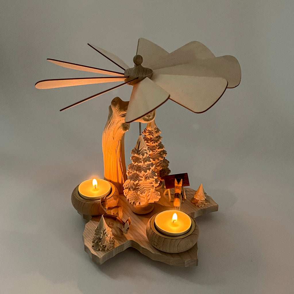 Wooden holiday carousel with a windmill and candles on a gray background