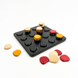 Colorful stone-like game pieces on a black tray with a white background