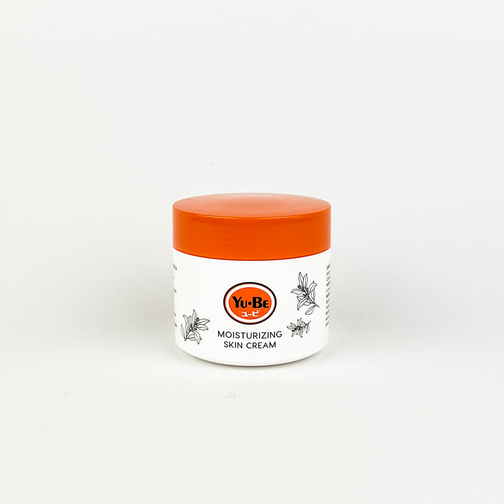Yu-Be moisturizing skin cream jar with orange lid on a white background