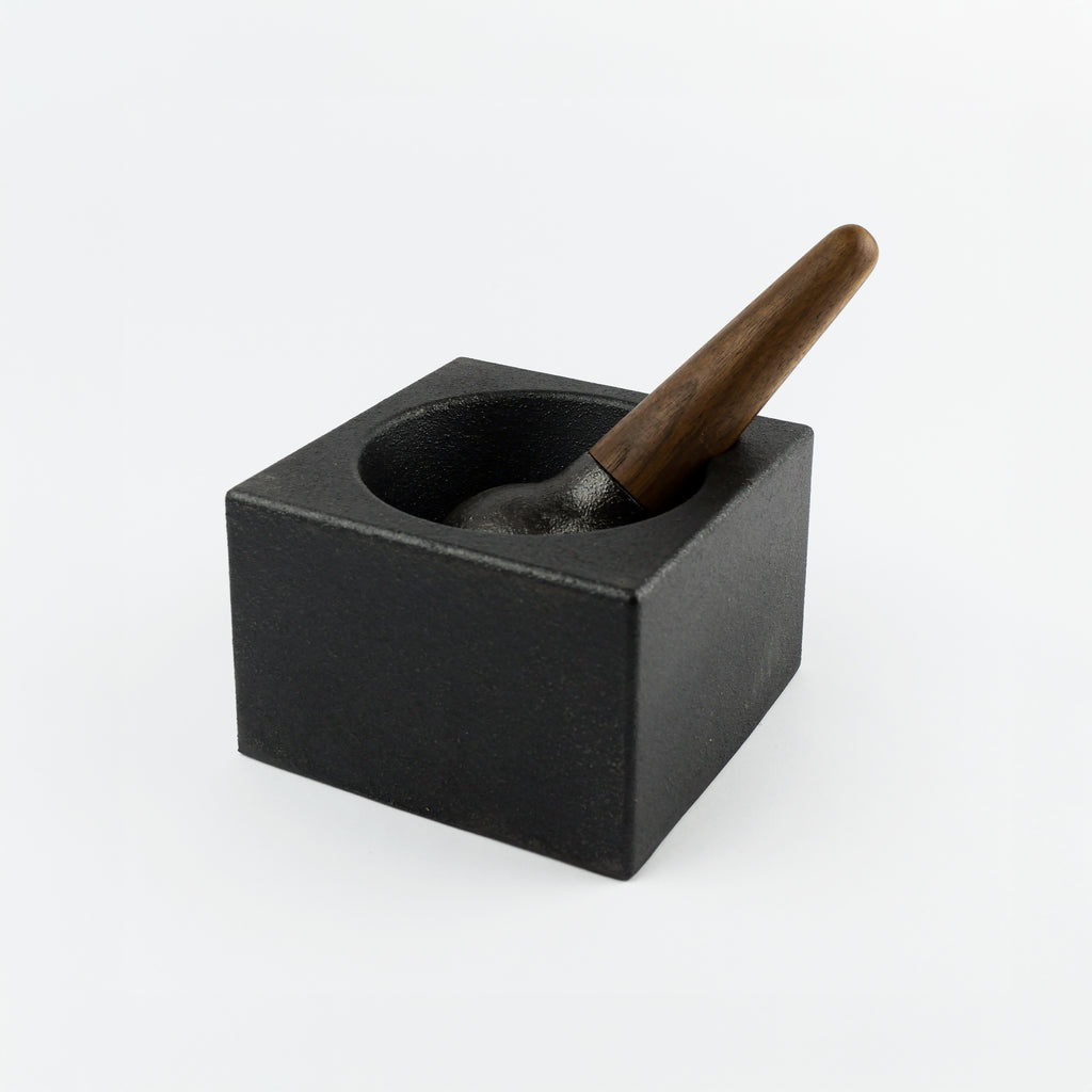 Black cast iron mortar and pestle on a white background