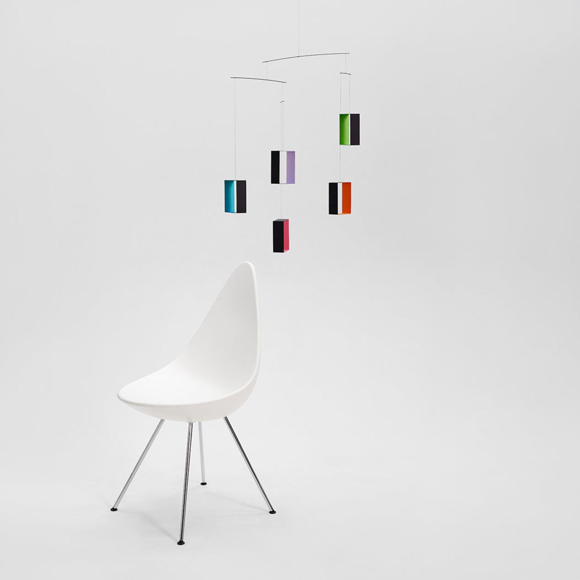 White chair with a colorful hanging mobile on a white background