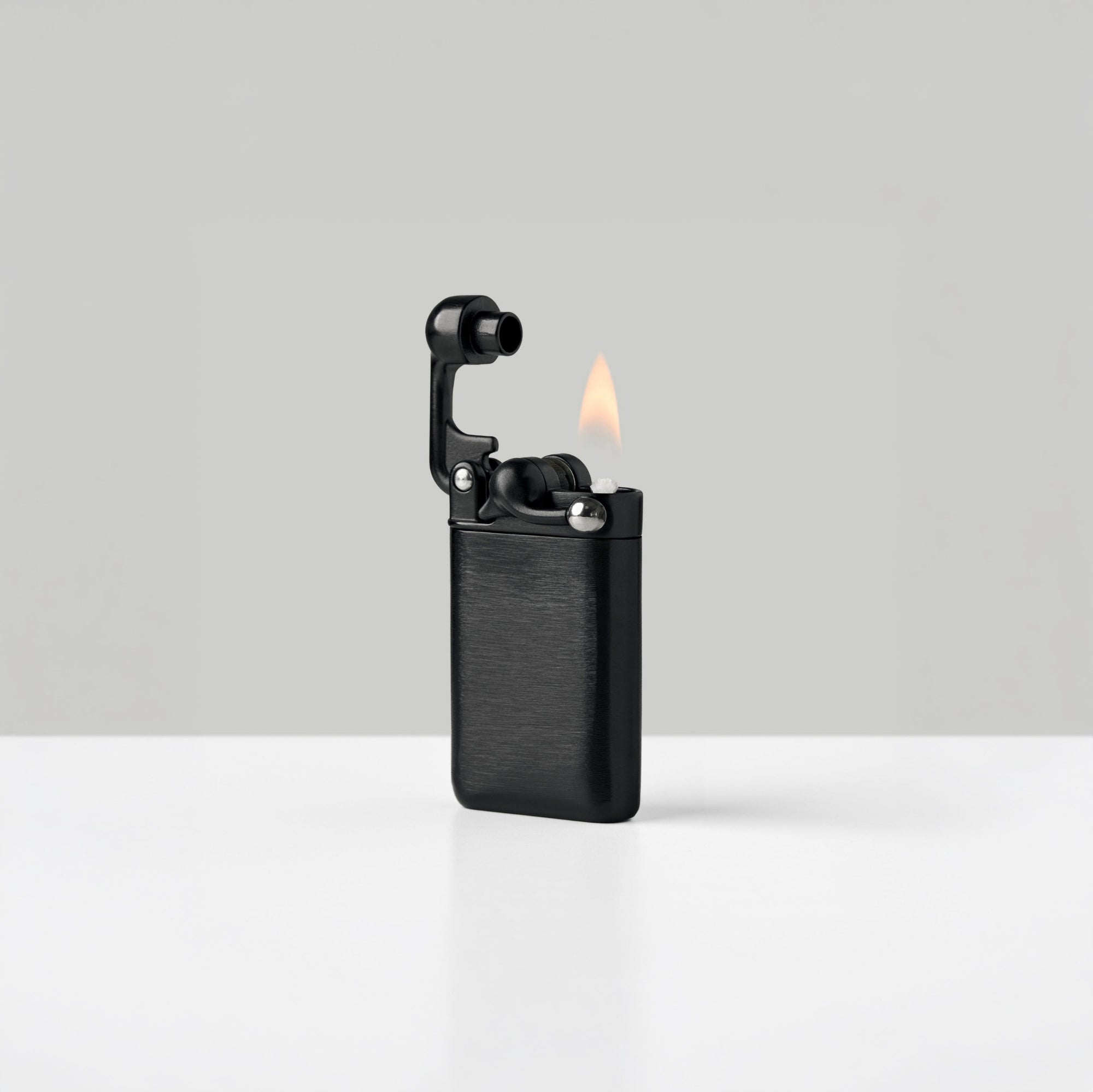 A black lighter with a textured metal body, shown open with a flame lit, set against a clean light gray background.
