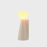 Decorative lamp with a beige base and glowing top on a light gray background