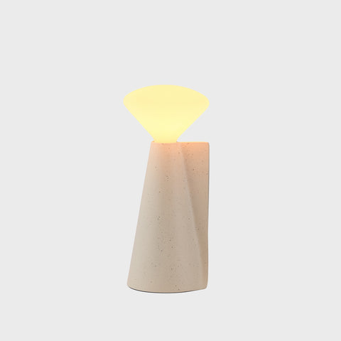 Decorative lamp with a beige base and glowing top on a light gray background