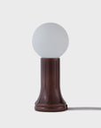 Small table lamp with a round white shade and brown base on a light gray background
