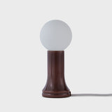 Small table lamp with a round white shade and brown base on a light gray background