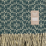 Woven fabric with a geometric pattern and brand label on a green background