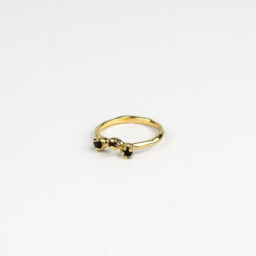 Gold ring with mixed dark  gemstones on a white background