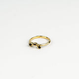 Gold ring with mixed dark  gemstones on a white background